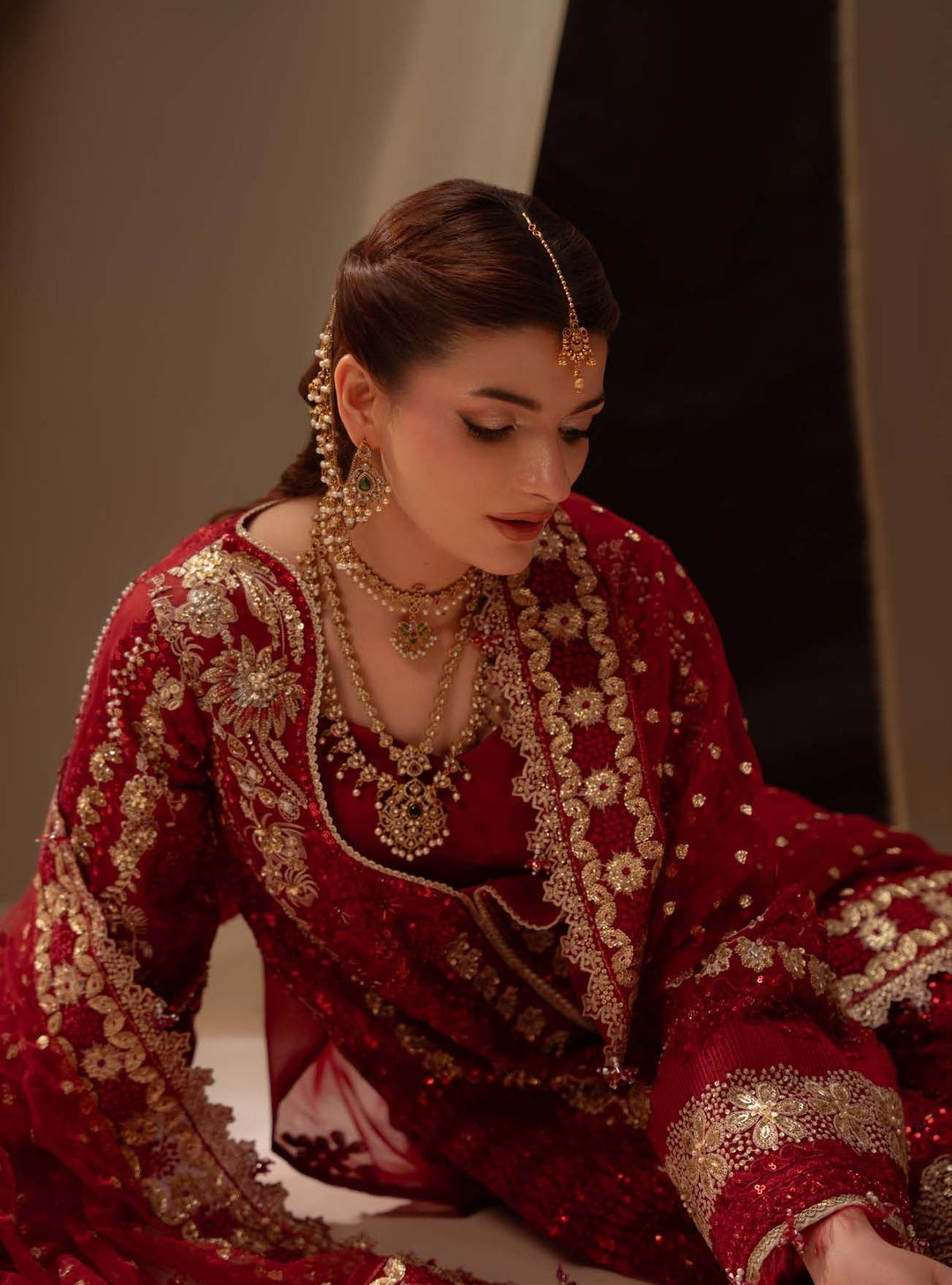 Close portrait wearing Amour with layered gold necklaces, looking down