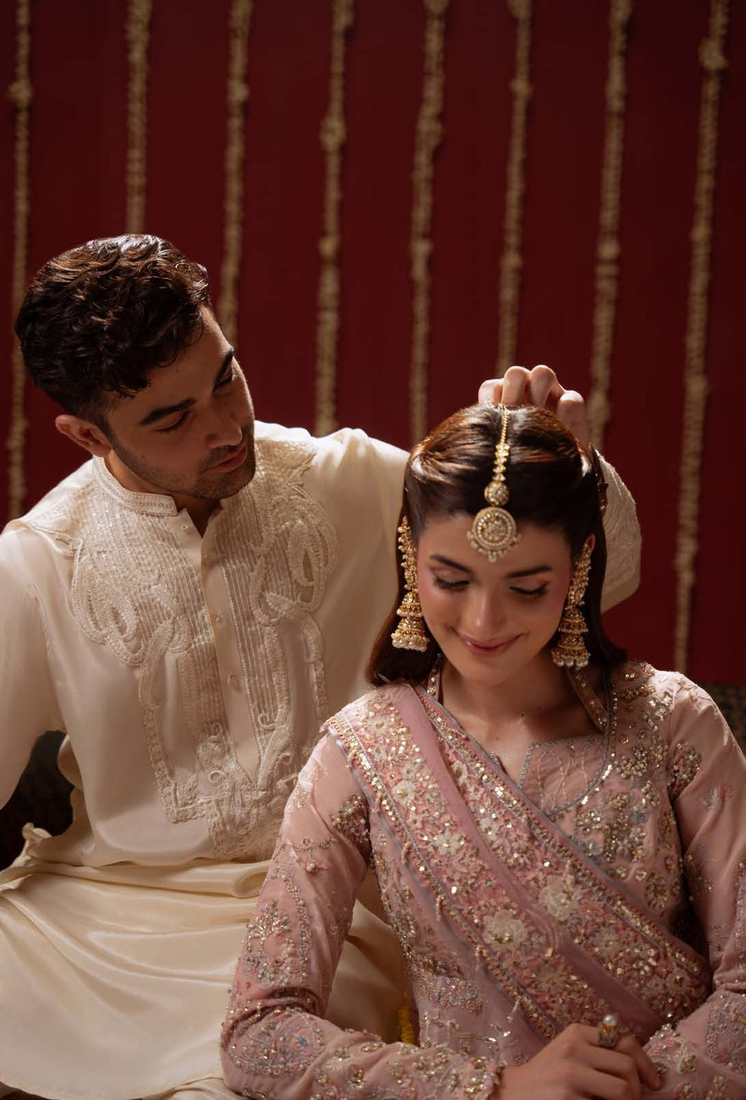 A man adjusting a gold tikka on the model wearing Lovelorn