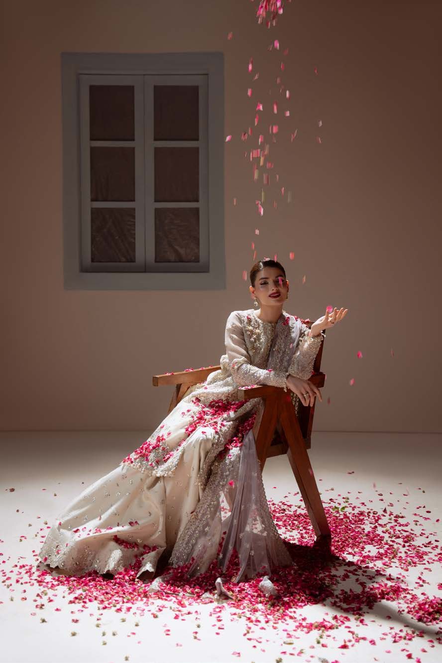 Enamour, the model seated on a wooden chair as rose petals fall