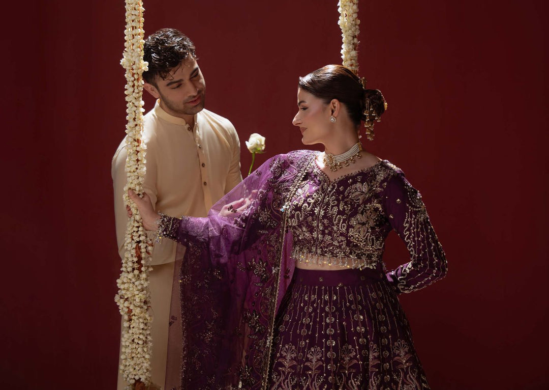 A wide shot of Ethereal: the model and a man in cream beside a swing hung with flower garlands