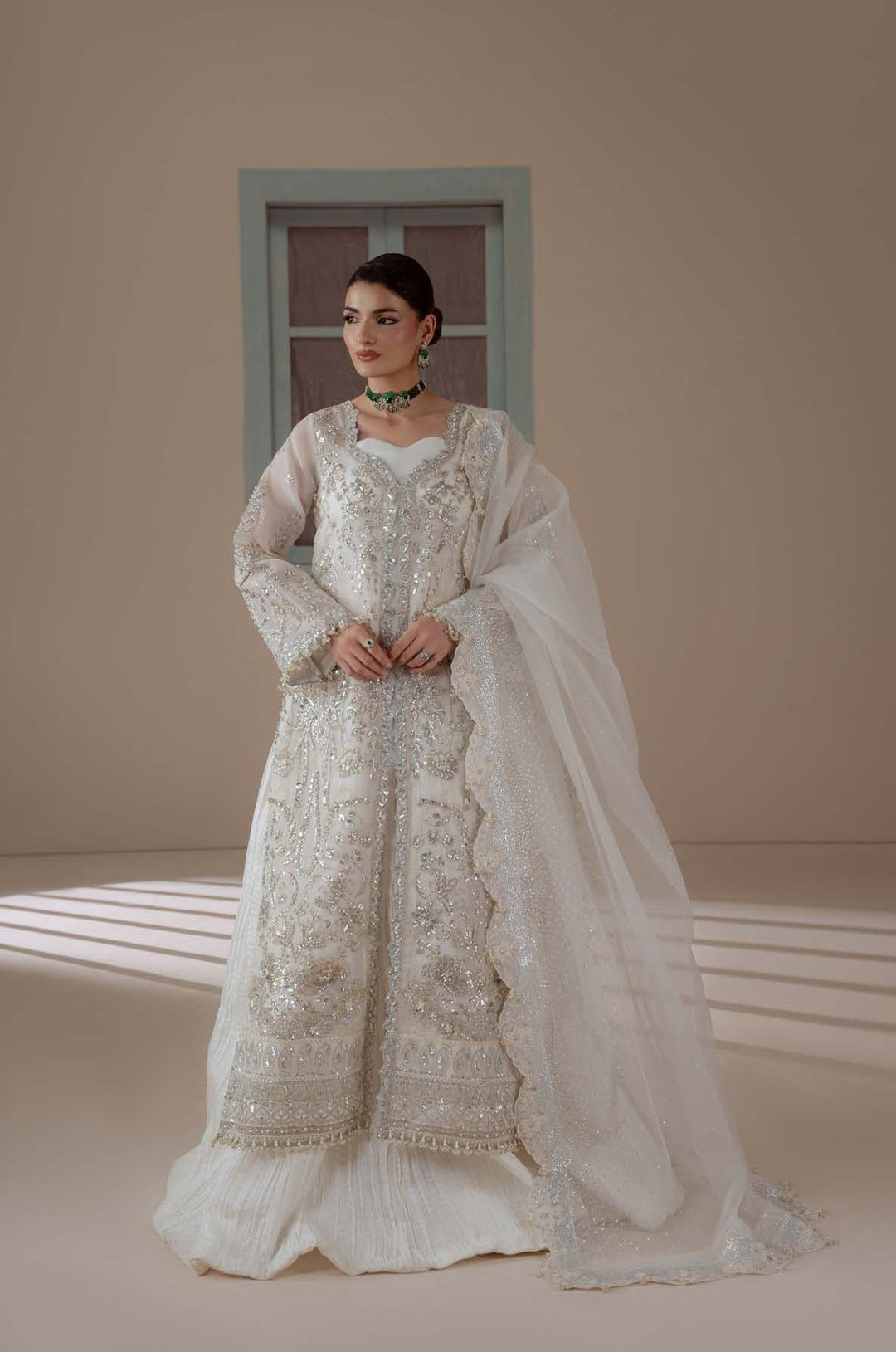 Serenity: an ivory long shirt with silver embellishment, standing before a pale blue window
