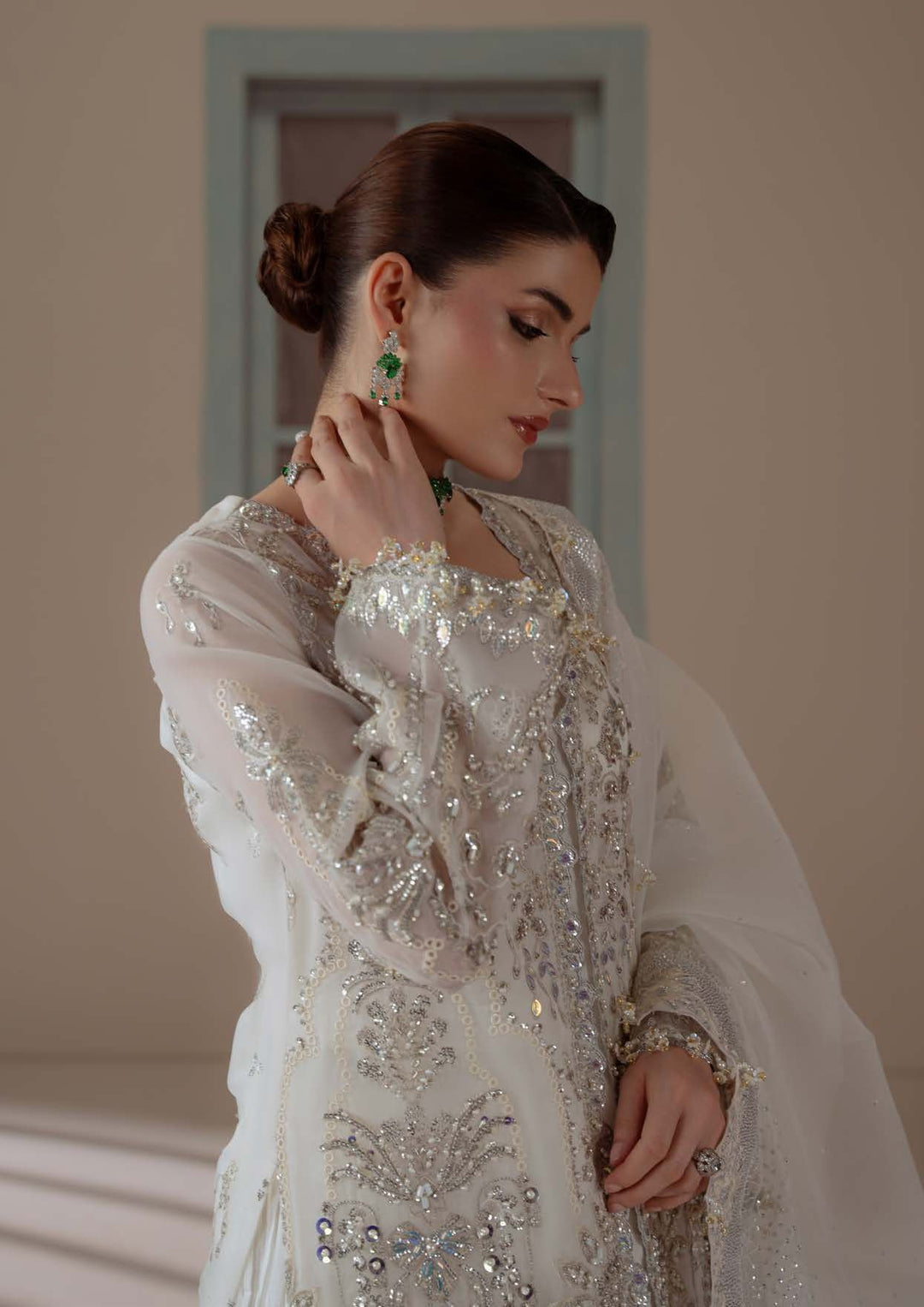Close portrait wearing Serenity with an emerald choker, a hand to the ear